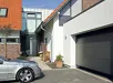 Hormann LPU 42 garagedeur in grijs, gemonteerd aan een modern huis met auto ervoor