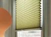 Gouden plisségordijn met handgreep voor raam