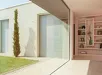 Moderne ingang met openstaande glazen rolluikdeur en inzicht in woonkamer met boekenplank