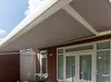 Knikarmzonwering boven overdekt terras met tafel en stoelen