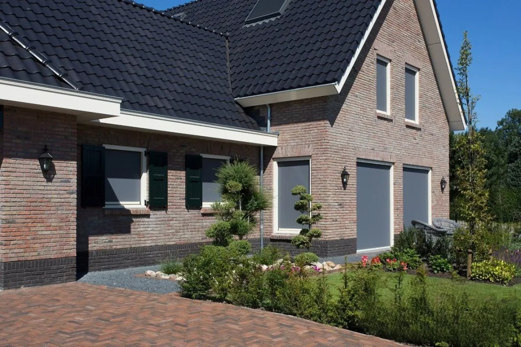 Donkerbruin uitvalscherm gemonteerd aan de gevel van een vrijstaande woning