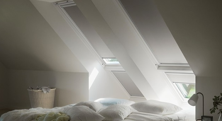 Dakraam met Velux zonwering in een slaapkamer met openstaande luiken en bed in de voorgrond