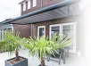 Knikarmscherm boven een terras met planten en meubels