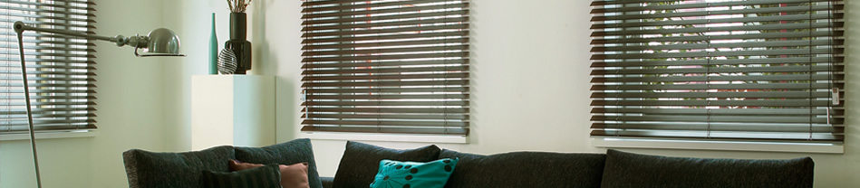 Moderne aluminium jaloezieën gesloten voor een raam in een woonkamer met donkere bank