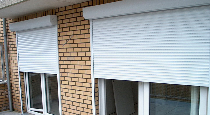 Gesloten wit rolluik onder een venster in baksteen gevel