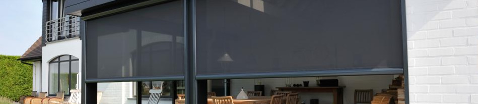 Grijze buitenzonwering gespannen voor grote schuifdeuren van een huis met terras