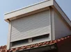 Wit rolluik op dakraam boven rood dak