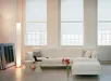 Witte bank met kussens en rode bloemen in lichte woonkamer met grote ramen