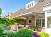 Witte woning met bruin dak en Ipanema Solar zonwering voor het raam