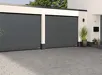 Twee donkergrijze Renomatic garagedeuren gemonteerd aan de gevel van een woning