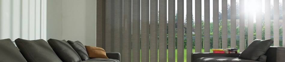 Grijze lamellen zonwering voor groot raam in woonkamer met donkere banken en tafel