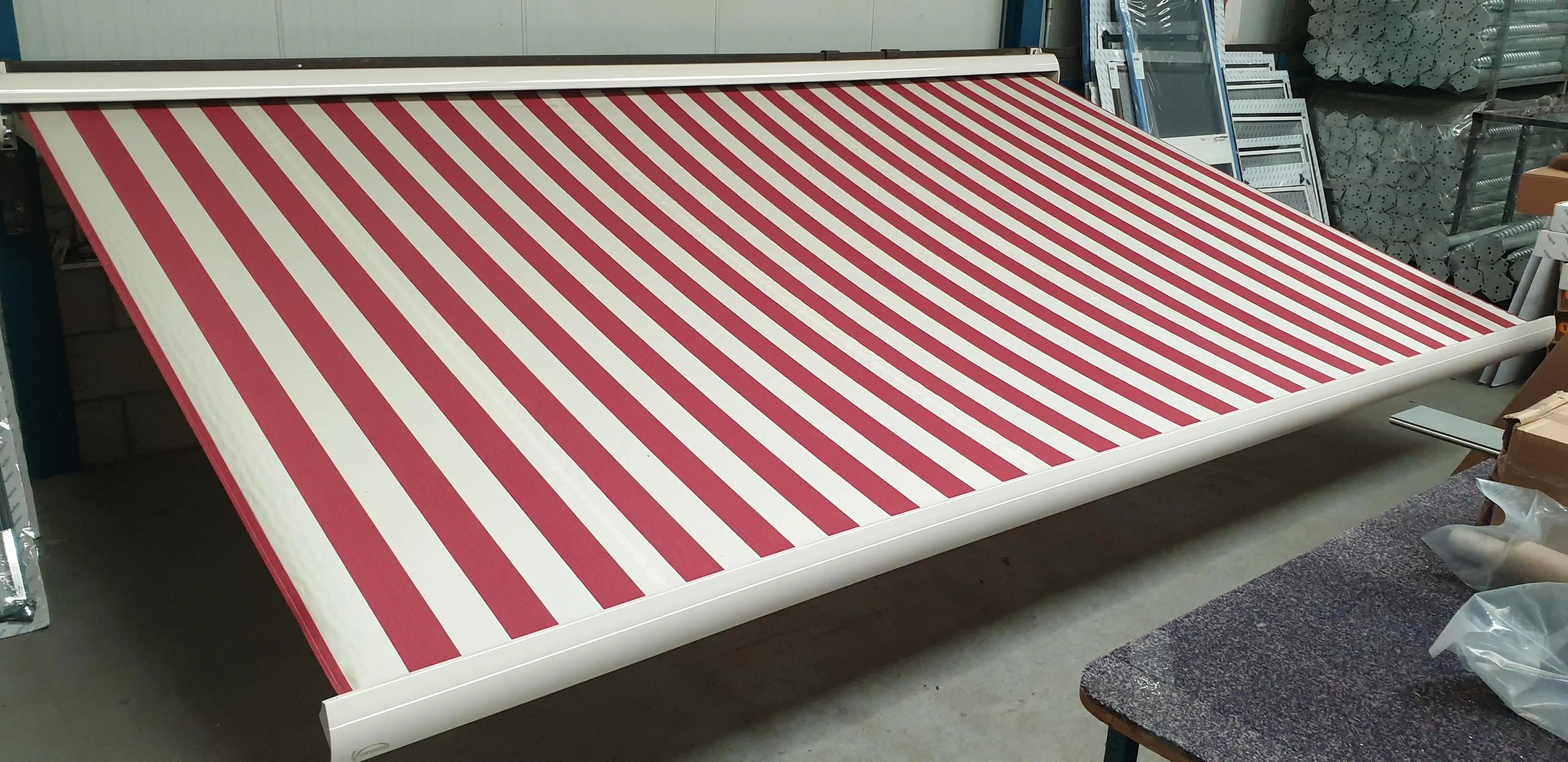 Rolzonwering met rode en witte verticale strepen op witte frame