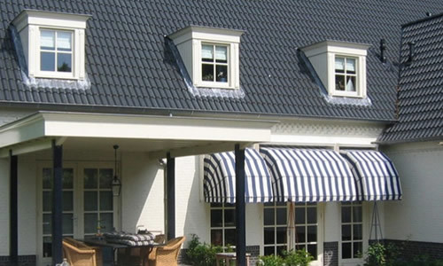 Wit-gestreepte markiezen voor raam onder dakvensters van een huis