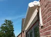 Knikarmscherm gemonteerd aan een bakstenen gevel, half open