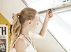 Vrouw met blonde haren die een insectenhor bij een raam controleert