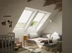 Kinderkamer met Velux dakraam en gordijn, speelhoek met kinderstoel en speelgoed