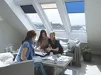 Drie vrouwen praten in woonkamer met Velux dakramen en blauwe gordijnen