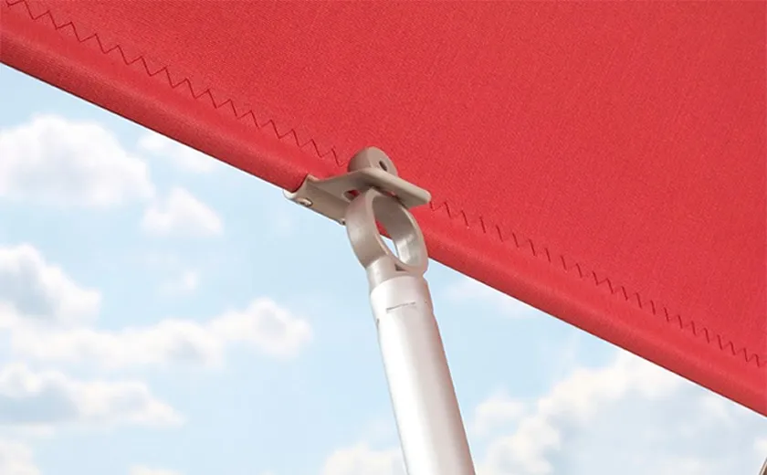 Bedieningsstok van Fakro zonwering bevestigd aan het rood gordijn met metalen klem