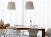 Tafel met stoelen en twee witte hanglampen achter een lamelgordijn