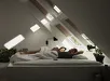 Bed in schuine slaapkamer met Velux daklichten en twee ontspannen personen op bed