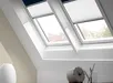 Twee Velux duo rolgordijnen in donkerblauw en wit in woonkamer onder dakraam