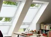Wit VELUX Solar Plissé gordijn voor raam met uitzicht op tuin