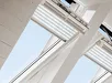 Witte lamellen van een VELUX plissé gordijn in een raamopening