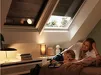 Grote witte Velux verduisterende buitenzonwering boven een woonkamer met twee personen