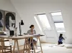 Vrouw werkt aan tafel bij VELUX dakraam met halfgesloten plissegordijn